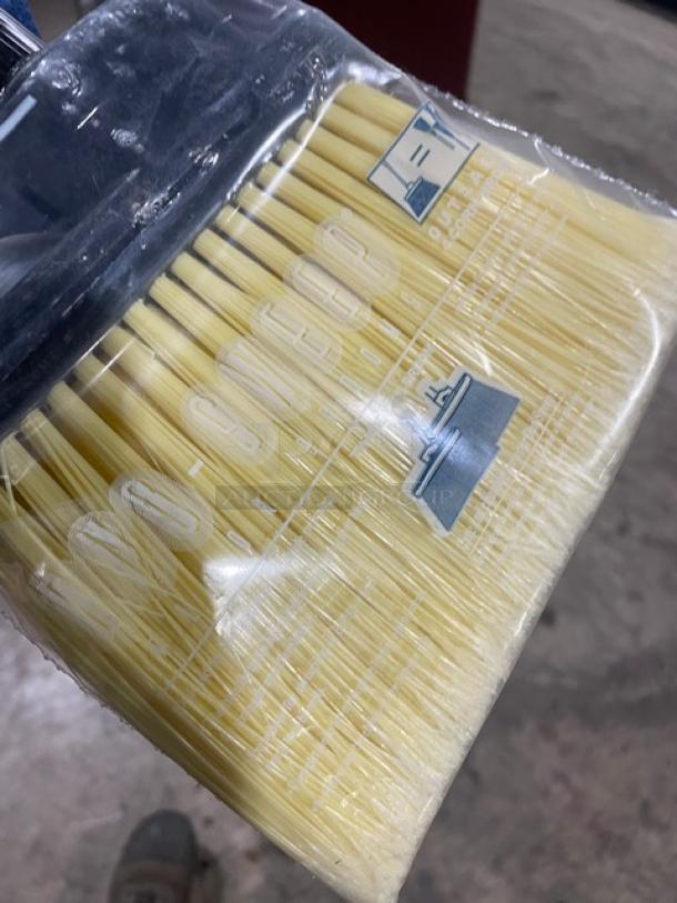 New commercial floor broom with yellow bristles, black grip handle, and protective plastic wrap; label shows "3X your bid."