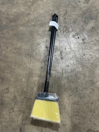 New commercial floor broom with yellow bristles, black grip handle, wrapped in plastic. Features a label "39".