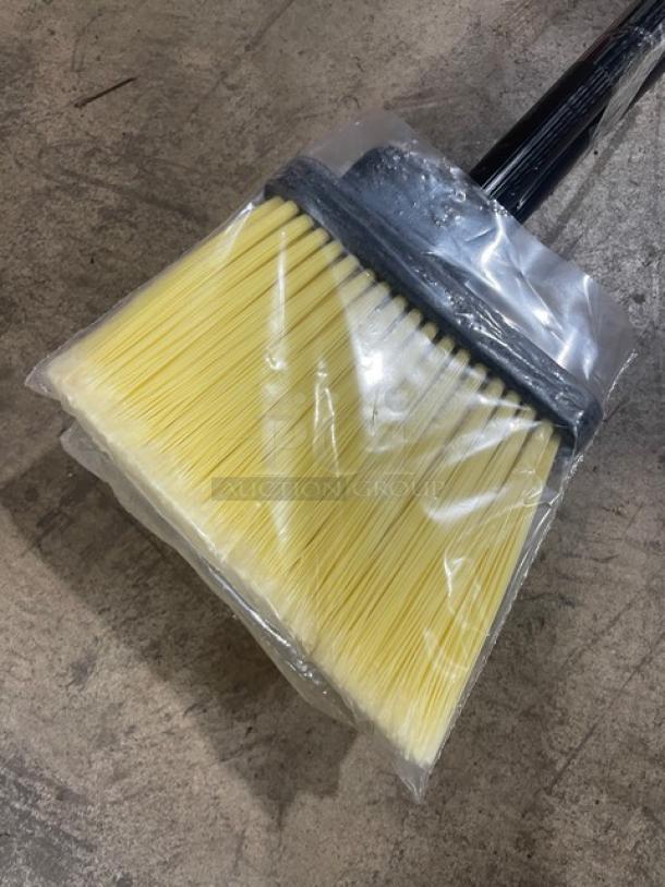 New commercial floor broom with yellow bristles, sealed in plastic. Features a sturdy black grip handle. Perfect condition.