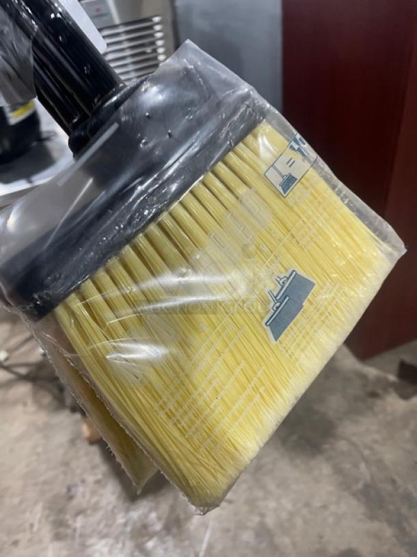New commercial floor broom with black grip handle, sealed in plastic. Features durable yellow bristles.
