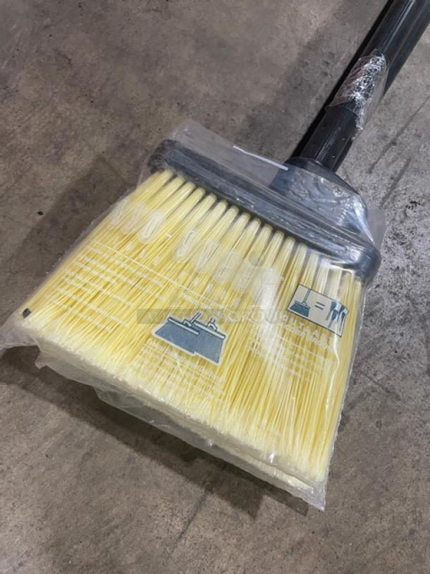 New commercial floor broom with yellow bristles and black grip handle, packaged in clear plastic.
