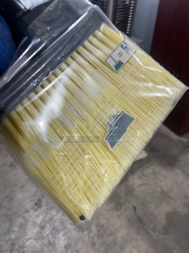 Commercial floor broom with yellow bristles, black grip handle, new in plastic packaging. Ideal for heavy-duty cleaning.