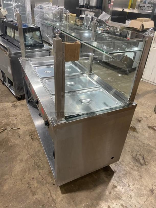 APW Wyott stainless steel 4-well hot food steam table with serve-over sneeze guard, on legs. Electric-powered.