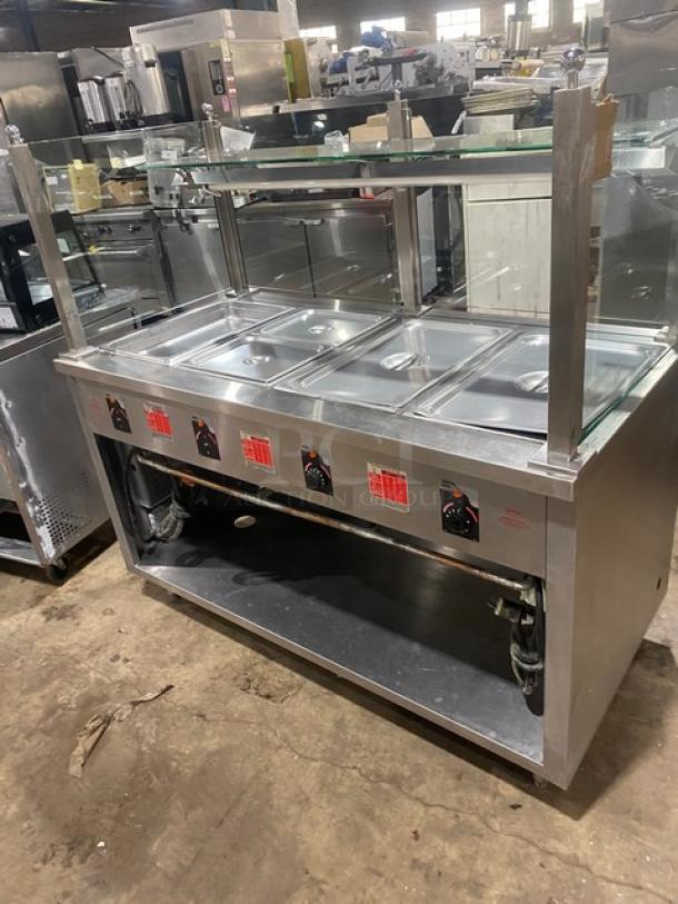 APW Wyott stainless steel 4-well hot food table with serve-over sneeze guard, electric powered, on legs, excellent condition.