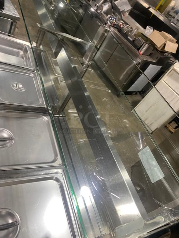 APW Wyott stainless steel 4-well hot food table with serve-over sneeze guard, electric powered, on legs, in used condition.
