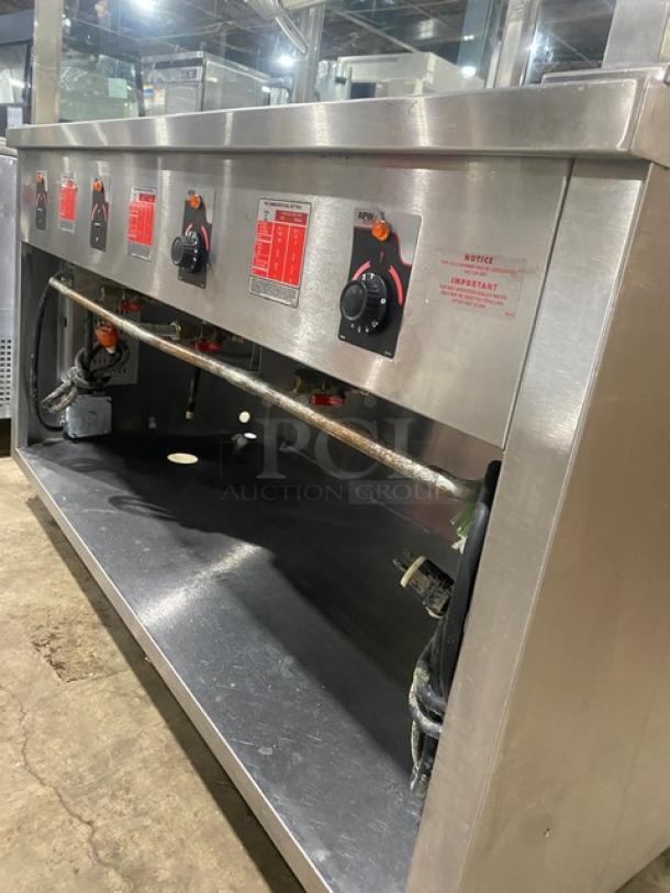 APW Wyott stainless steel 4-well hot food table with sneeze guard; electric-powered, commercial use, on legs.