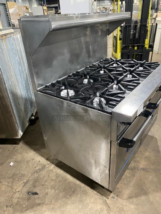 U.S. Range commercial stainless steel 8 burner range with double ovens, backsplash, overhead salamander shelf, and wired racks.