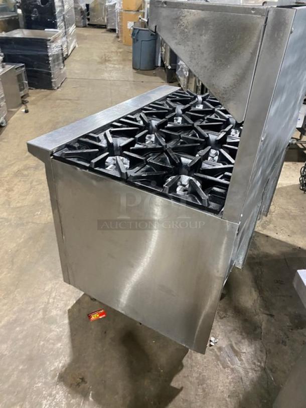 U.S. Range commercial stainless steel 8-burner range/double oven combo with backsplash, overhead salamander shelf, and wired racks.