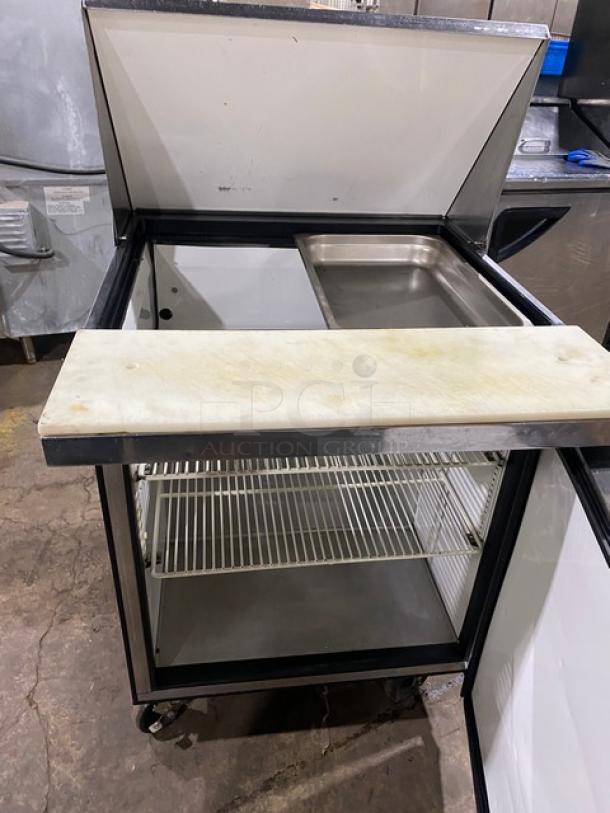 True TSSU-27-12M-C stainless steel single door prep table with cutting board, wire rack, on casters. Model TSSU2712MC.