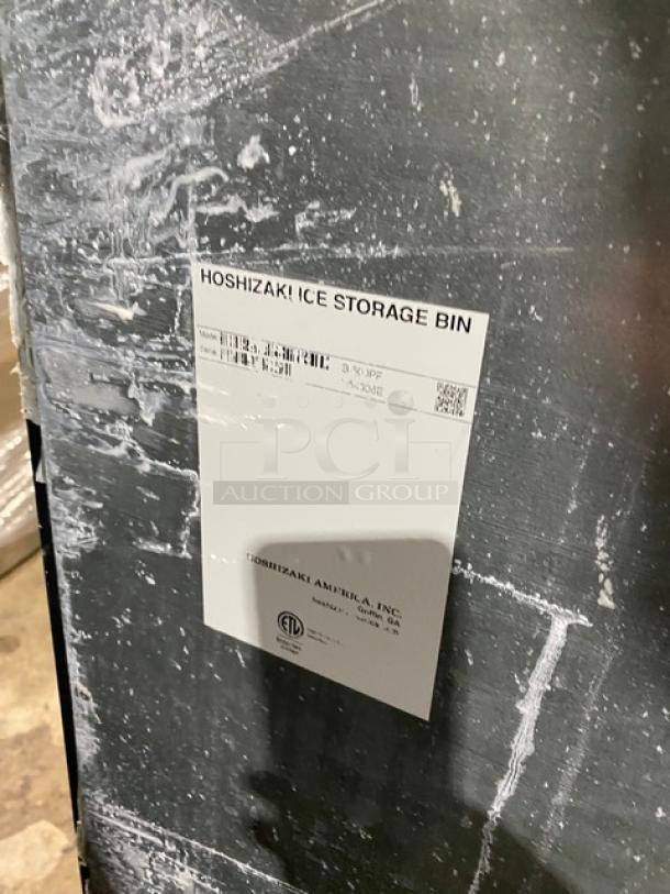 Hoshizaki commercial ice machine/storage bin combo with label indicating model and make, stainless steel, on legs.