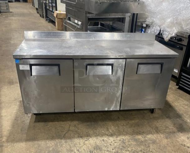 True TWT-72 stainless steel 3-door refrigerated worktop table, Energy Star certified, with upturned backsplash, on casters.