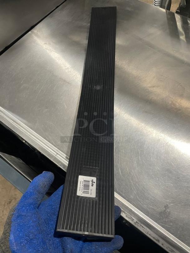 New Update International 27" black rubber bar mat, model BM-27BK, on a metal table; features ribbed texture, barcode tag visible.