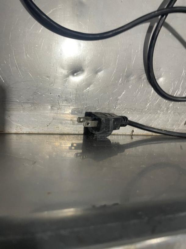 Power cord and plug of Omcan THV1200-380 refrigerated display case. Stainless steel backdrop. 110V connection.