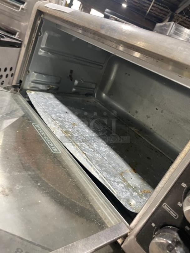 BLACK+DECKER TO3250XSB stainless steel countertop convection toaster oven, extra wide, 120V, on legs, visible wear inside.