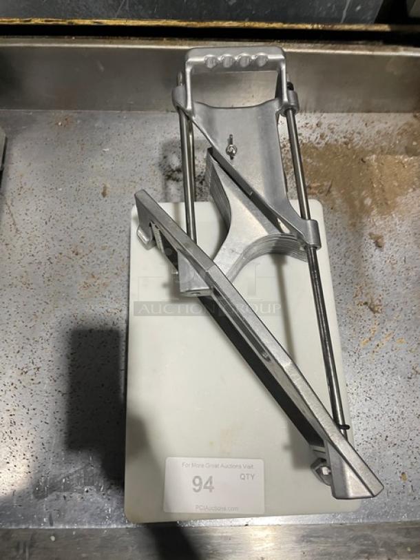 Commercial heavy-duty countertop tomato/vegetable slicer with cutting board, on legs. Features metal construction and easy slicing.