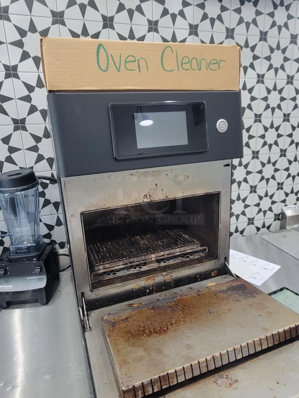 Practica Copa Express high-speed oven in used condition, black model, with visible wear. Bonus oven cleaner box included.