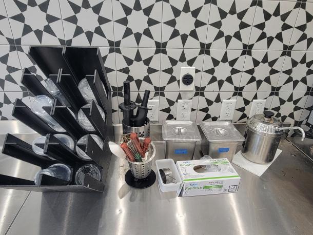 Commercial kitchen supplies lot, including utensil holders, condiment containers, plastic cups, and poly gloves in good, used condition.