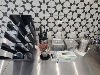 Commercial kitchen supplies lot, including utensil holders, condiment containers, plastic cups, and poly gloves in good, used condition.