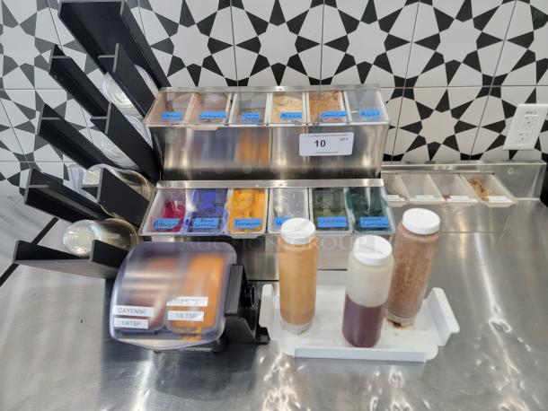 Lot of smoothie bar toppings dispenser; labeled containers with cacao, turmeric, spirulina; includes squeeze bottles; good condition.