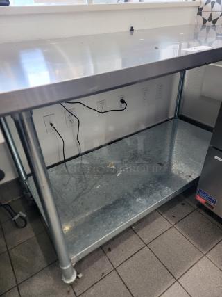 5' stainless steel work table on casters, features a lower shelf, minor surface wear, ideal for industrial use.