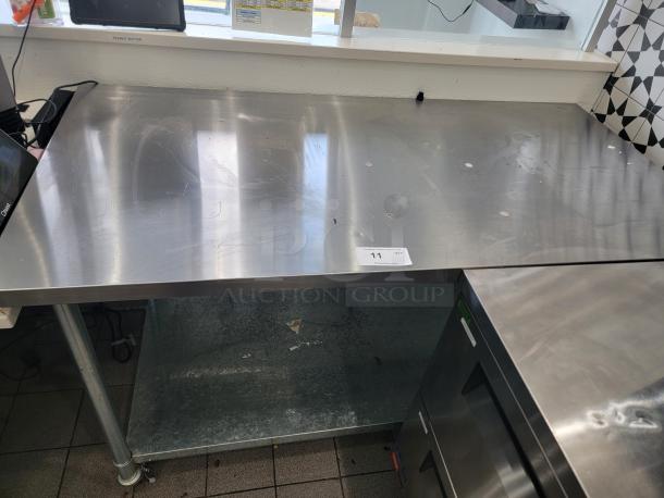 5-foot stainless steel work table on casters, scratches on surface, includes lower shelf. Auction tag indicates item 11.
