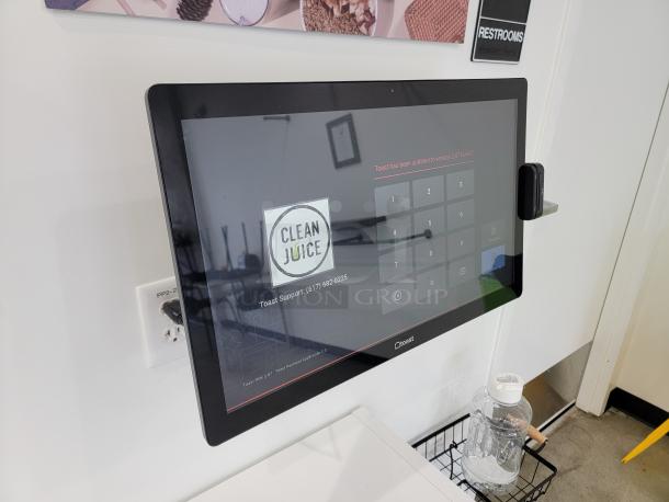 Toast POS system mounted on wall with user interface screen visible, clean condition, ideal for business operations.