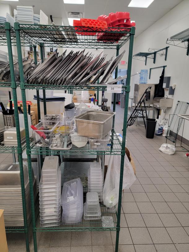 Bulk lot of stainless steel food pans and lids on a green Metro rack; includes various sizes, ideal for commercial kitchen use.