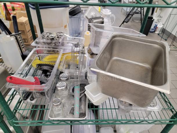 Bulk lot of stainless steel food pans and lids in various sizes, displayed on a green Metro rack. Ideal for food service settings.