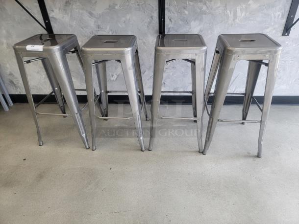 Stackable metal bar stools in silver/gray, modern industrial style, durable, sleek design, suitable for kitchen or bar use.
