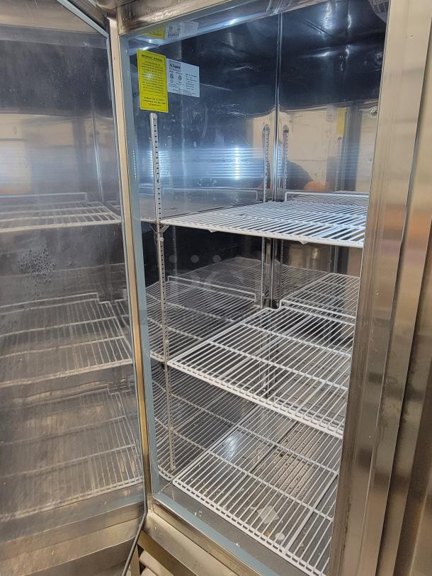 Supera PCF3-SI-HC 3-Door Commercial Refrigerator, stainless steel interior, multiple wire shelves, inspection stickers visible.