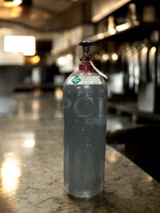 BBI beverage-grade CO2 tank on a countertop, great condition, fully tested. Features a red valve and attached label.