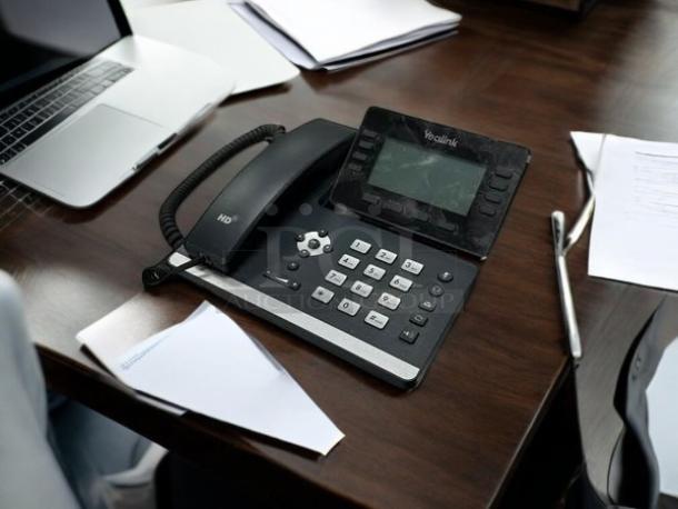 Yealink SIP-T53W office phone with display and keypad, in good condition on a wooden desk.