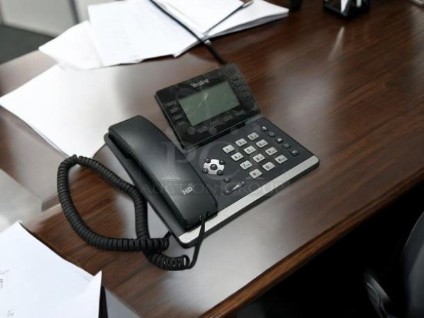 Yealink SIP-T53W desk phone on wooden surface, featuring HD audio, large screen, and keypad. Model number visible.
