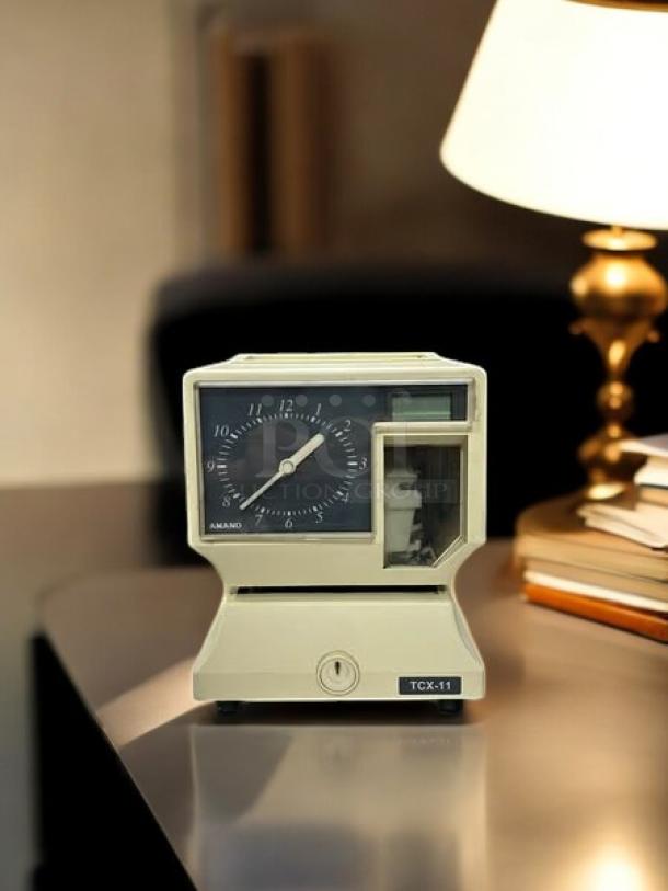 AMANO TCX-11 time clock, great condition, 6 7/8in W, 8 1/4in H, fully tested and working, clear display, visible brand label.