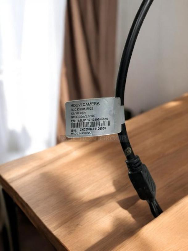 Dahua HDCVI security camera cable with label showing model, serial number, and made in China tag, on wooden surface.
