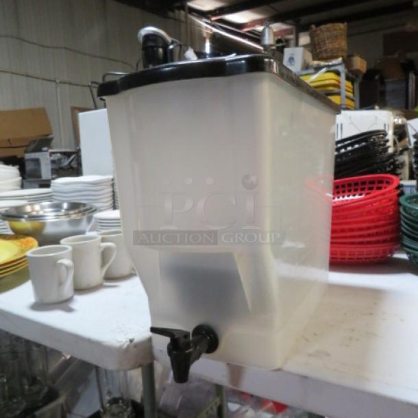Translucent beverage dispenser with black lid and spigot, showing wear. Used condition, suitable for dispensing various drinks.