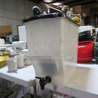 Translucent beverage dispenser with black lid and spigot, showing wear. Used condition, suitable for dispensing various drinks.