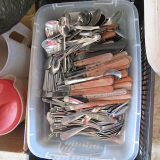 Mega lot of mixed flatware in plastic container; includes spoons, knives, forks with wooden and metal handles, used condition.