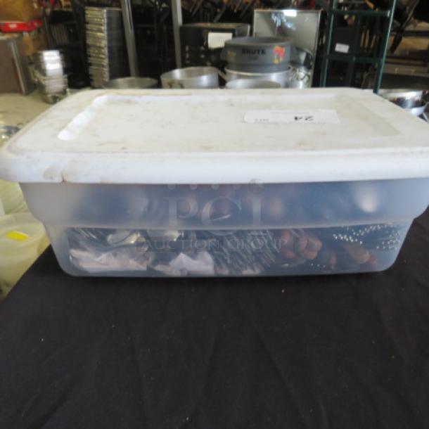 Clear plastic storage bin containing assorted flatware. Bin appears partially filled and has a label on the lid.