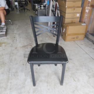 Black metal chair with cushioned seat, crisscross back design, sturdy frame, slightly worn condition, ideal for home or office.