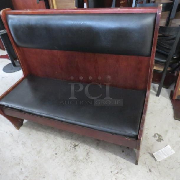 Wooden booth with black cushioned seat and back, single-sided, excellent condition, ideal for restaurants or cafes.