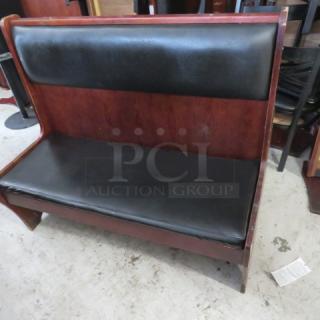 Wooden booth with black cushioned seat and back, single-sided, excellent condition, ideal for restaurants or cafes.