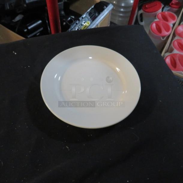 A collection of approximately 30 seven-inch white plates in good condition, displayed on a black surface.