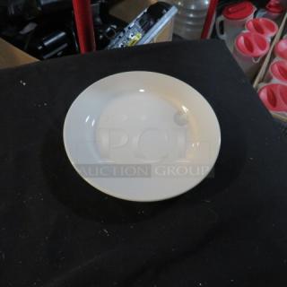 A collection of approximately 30 seven-inch white plates in good condition, displayed on a black surface.