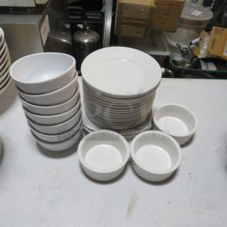 Assorted white dishware set including plates, bowls, and ramekins in good condition, displayed on a table.