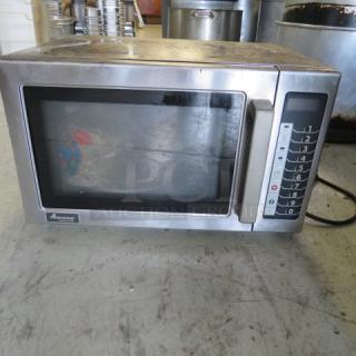 Stainless steel Amana microwave, Model RCS10TS, 120V, 22x16x14 inches, visible controls and Amana logo, used condition.