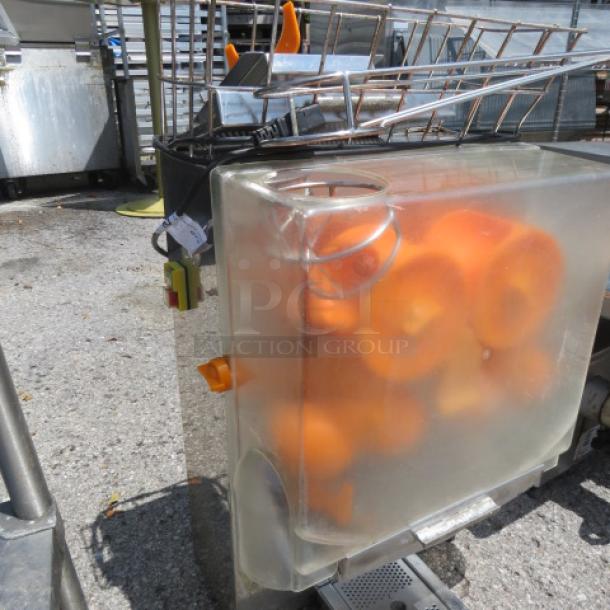 Commercial juicer model XC-2000E-2. Transparent casing shows orange fruits. Includes controls and spout. 110 Volt.