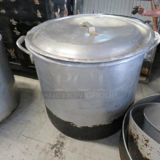 Aluminum stock pot with lid, 23x19 inches, features sturdy handles and visible wear, ideal for large-capacity cooking.