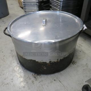 Aluminum stock pot with lid, 21x12 inches, used condition with wear marks, metal handles.
