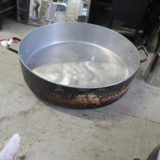 Large aluminum braizing pan with handles, 24"x7", showing wear on exterior. Ideal for heavy-duty cooking.